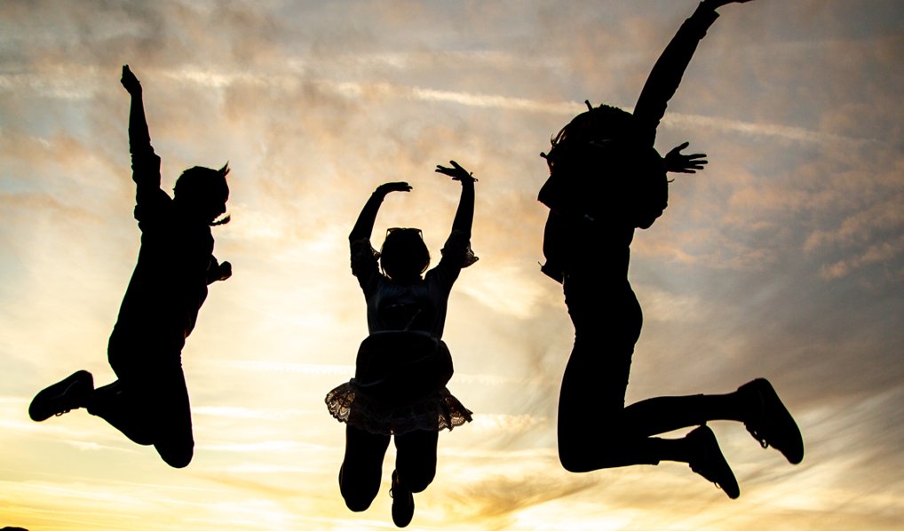 A silhouette of three teenagers jumping in the air.
